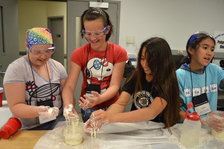 Four students working in a lab with some beakers and other lab equipment