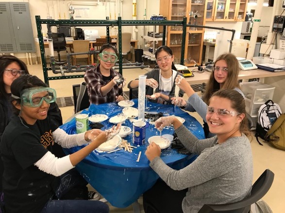 Campers working on lab activites in a group, wearing goggles 